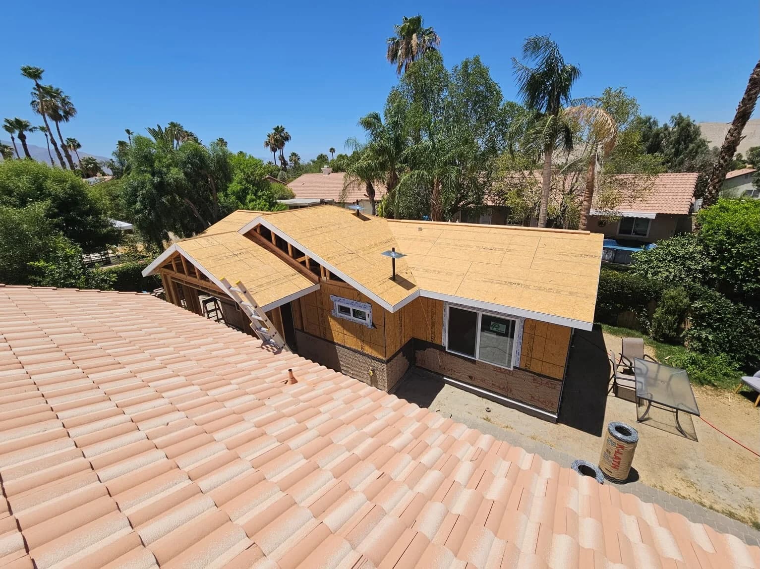 Exposed wood decking on the roof behind the foreground tile roof